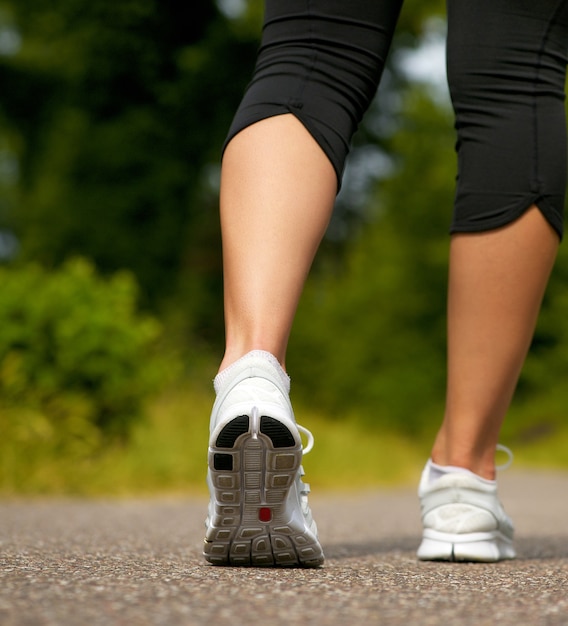 Jonge vrouw die in witte tennisschoenen in openlucht loopt