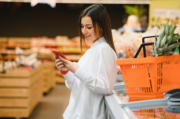 Jonge vrouw die informatie over het product aan de telefoon leest