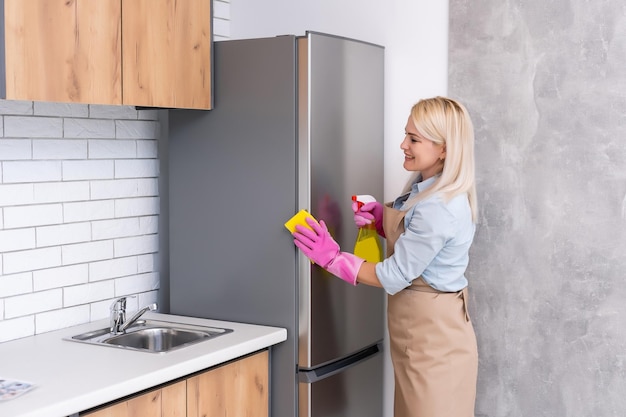 Jonge vrouw die keukenkasten schoonmaakt