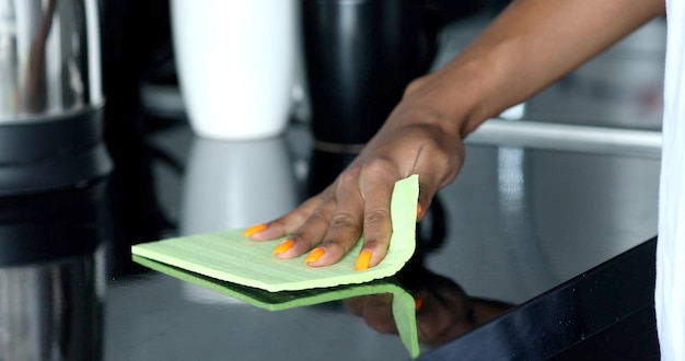 Jonge vrouw die keukentafel schoonmaakt.