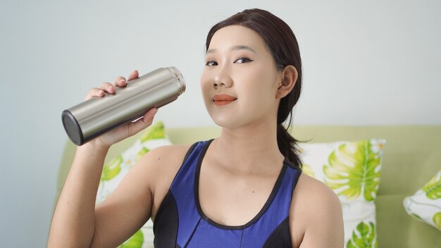 Jonge vrouw die klaar was met yoga drinkwater in haar fles