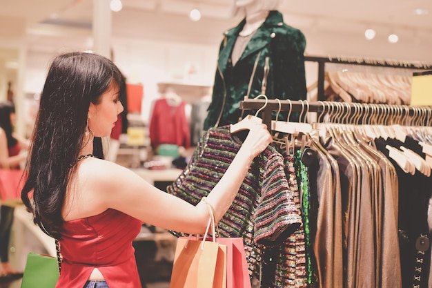 Jonge vrouw die kleren koopt in een winkelcentrum