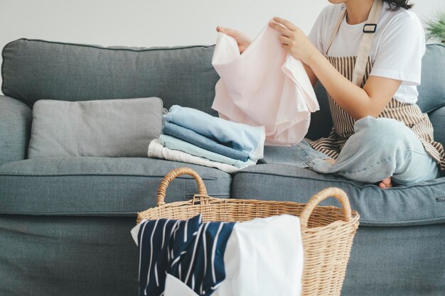 Jonge vrouw die kleren op de bank thuis vouwt