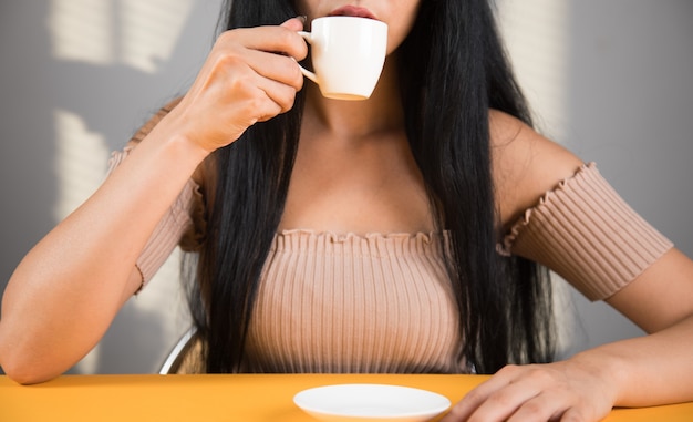 Jonge vrouw die koffie drinkt aan tafel