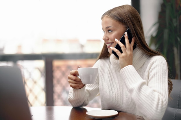 Jonge vrouw die koffie drinkt en telefoon praat