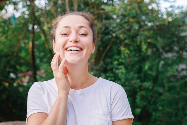 Jonge vrouw die lacht buiten. Mooi brunete meisje rustend op park of tuin groene achtergrond. Gratis gelukkige vrouw in de zomer. Vrijheid geluk zorgeloos gelukkige mensen concept.