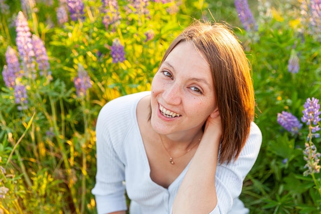 Jonge vrouw die lacht buiten mooi brunete meisje rustend op zomer veld met bloeiende wilde bloem