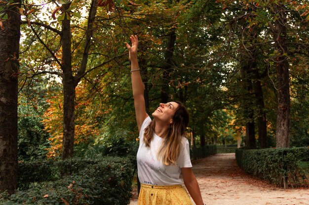 Jonge vrouw die lacht in een park in de herfst spelen met bladeren. Selectieve aandacht.