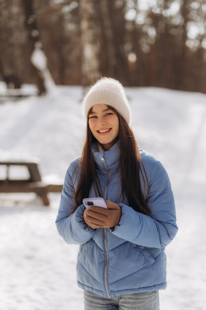 Jonge vrouw die lacht met slimme telefoon en winterlandschap