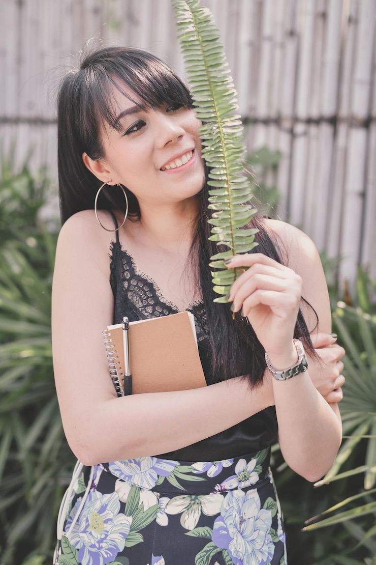 Foto jonge vrouw die lacht terwijl ze tegen planten staat
