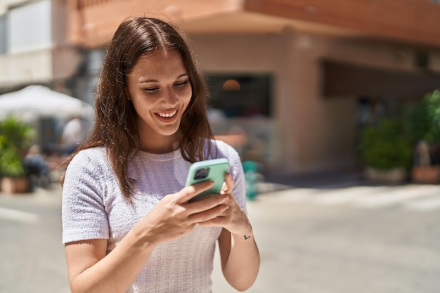 Jonge vrouw die lacht zelfverzekerd met behulp van smartphone op straat