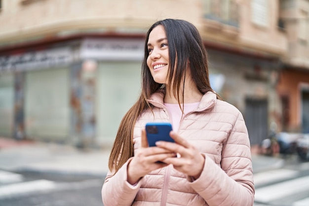 Jonge vrouw die lacht zelfverzekerd met behulp van smartphone op straat