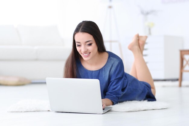 Jonge vrouw die laptop binnenshuis gebruikt