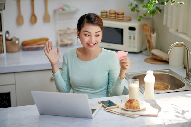 Jonge vrouw die laptop en creditcard thuis gebruikt