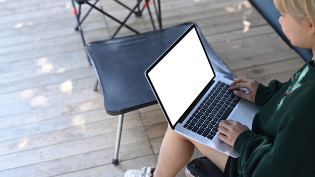 Jonge vrouw die laptop gebruikt terwijl ze op een klapstoel zit