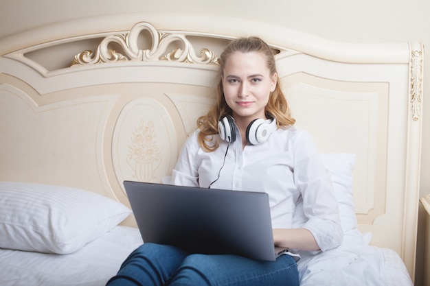 Jonge vrouw die laptop op het bed met behulp van