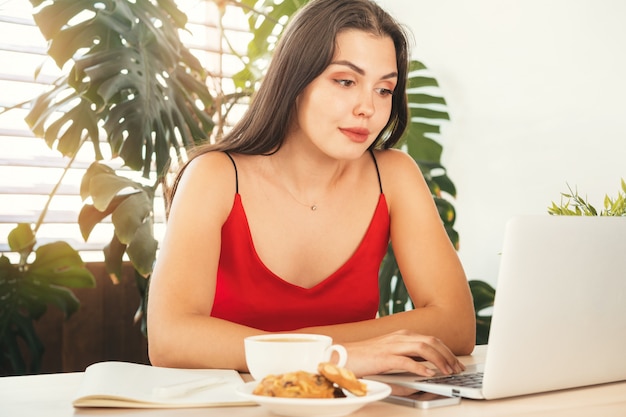 Jonge vrouw die laptop thuis of in koffie met behulp van