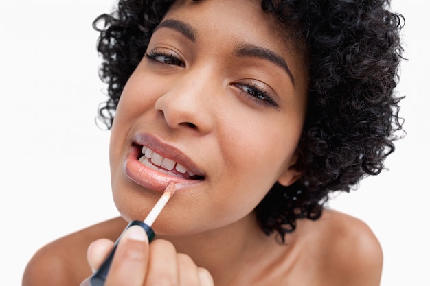 Jonge vrouw die lippenstift op een geconcentreerde manier toepast