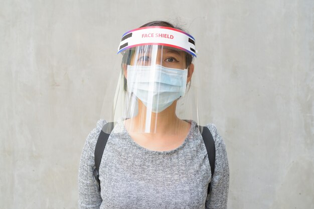 Foto jonge vrouw die masker en gezichtsscherm draagt ter bescherming tegen uitbraak van het coronavirus buitenshuis