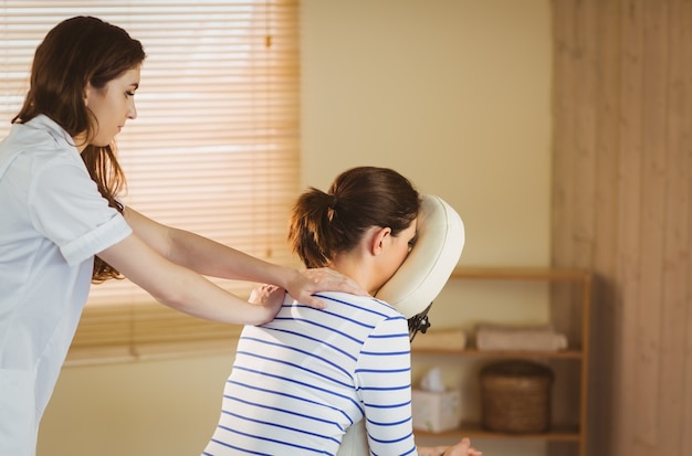 Jonge vrouw die massage als voorzitter krijgt