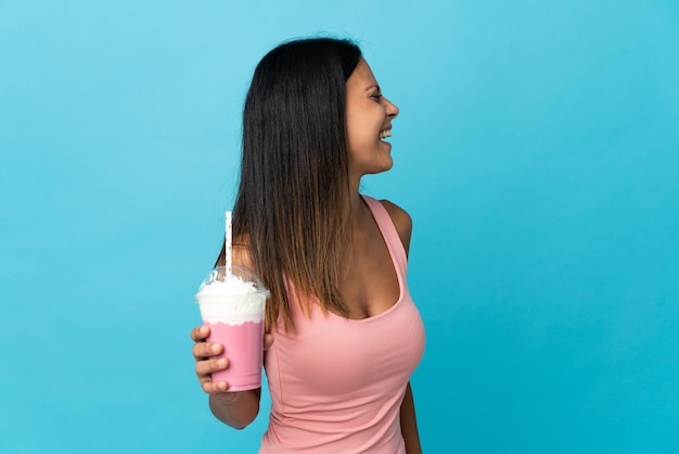 Jonge vrouw die met aardbeimilkshake in zijpositie lachen