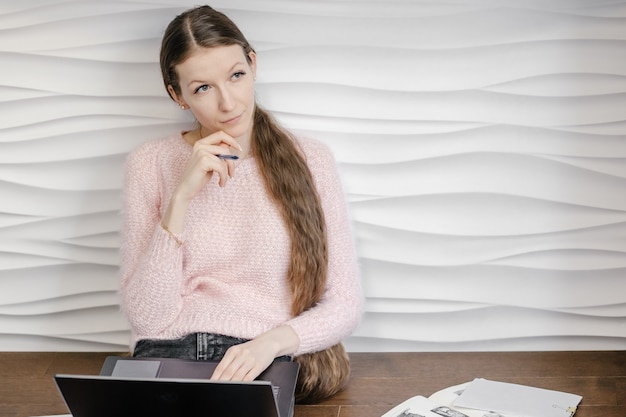 Jonge vrouw die met boeken en laptop bestudeert