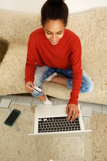 Jonge vrouw die met creditcard en laptop winkelt