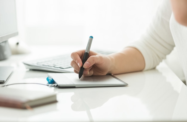 Jonge vrouw die met digitale grafische tablet werkt