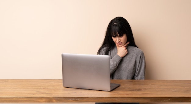 Jonge vrouw die met haar laptop het denken werkt