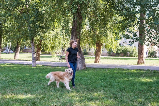 Jonge vrouw die met haar retrieverhond in het park loopt