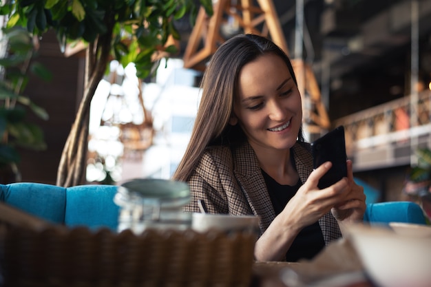 Jonge vrouw die met in hand smartphone glimlachen