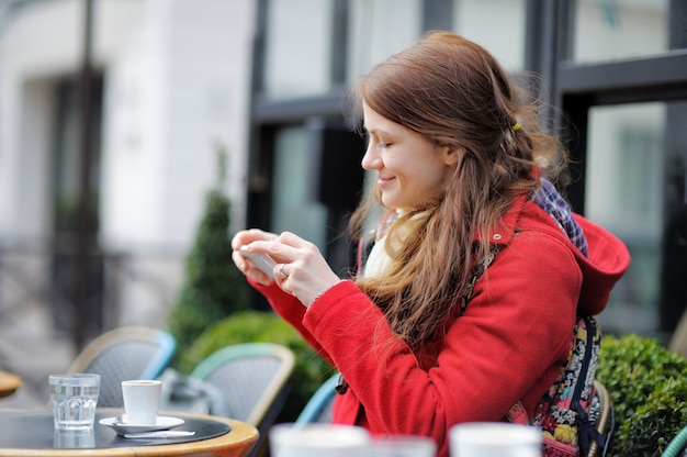 Jonge vrouw die mobiele foto van haar kop van koffie in een Parijse straatkoffie neemt