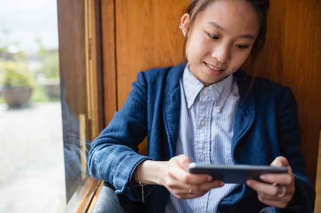 Jonge vrouw die mobiele telefoon in bureau met behulp van