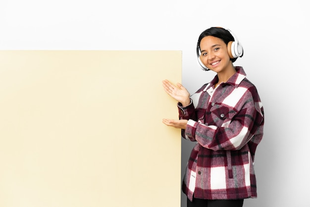 Jonge vrouw die muziek luistert met een groot leeg bordje over een geïsoleerde achtergrond die haar handen naar de zijkant uitstrekt om uit te nodigen om te komen
