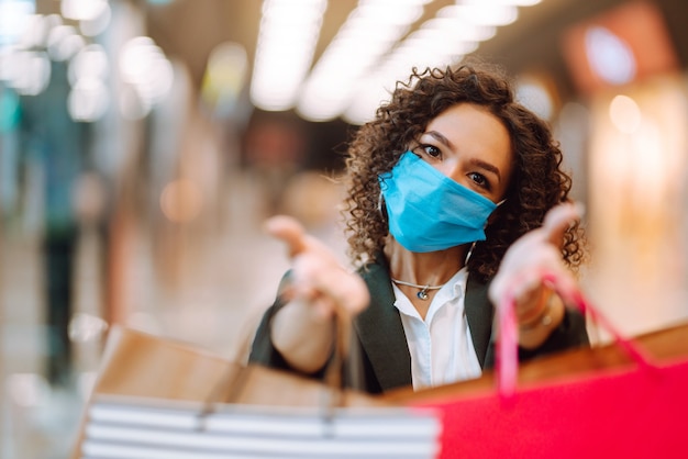 Jonge vrouw die na het winkelen een beschermend gezichtsmasker draagt tegen het coronavirus.