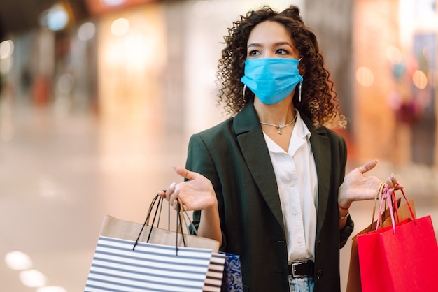 Jonge vrouw die na het winkelen een beschermend gezichtsmasker draagt tegen het coronavirus.