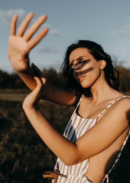 Jonge vrouw die naar de zon kijkt, haar gezicht bedekt