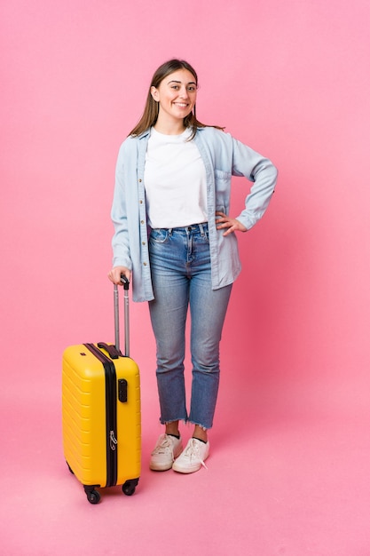 Jonge vrouw die naar reiziger gaat die op roze muur wordt geïsoleerd