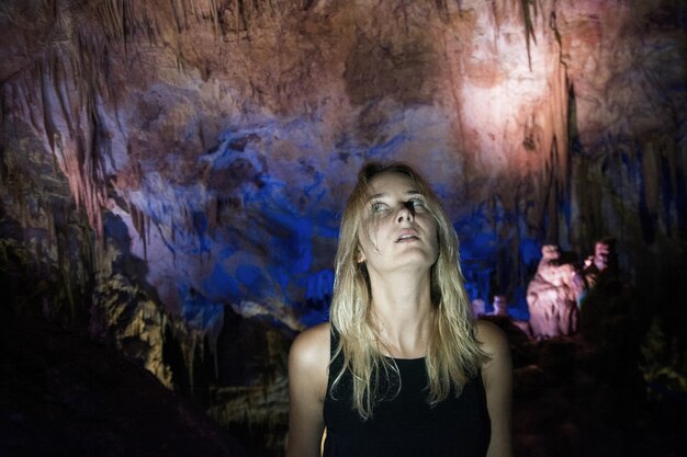 Foto jonge vrouw die omhoog kijkt terwijl ze in de grot staat