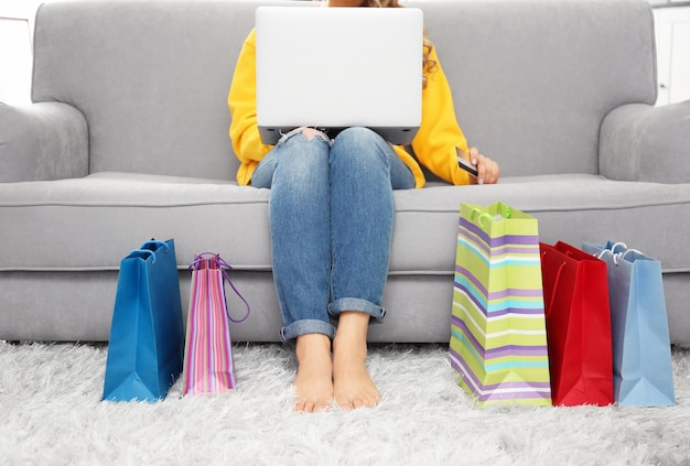 Foto jonge vrouw die online met creditcard en laptop thuis winkelt