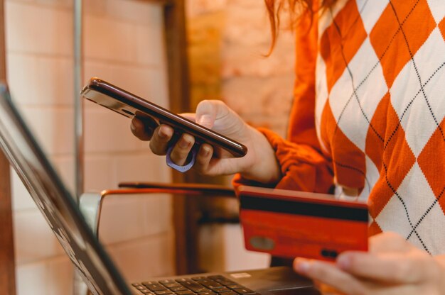jonge vrouw die online winkelt met laptoptelefoon en creditcard