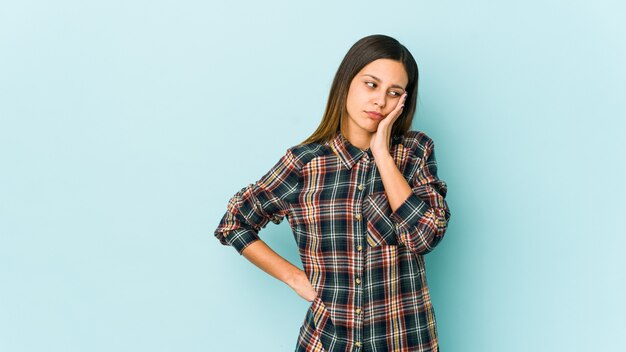 Jonge vrouw die op blauwe muur wordt geïsoleerd die verveeld, vermoeid is en een ontspannende dag nodig heeft.