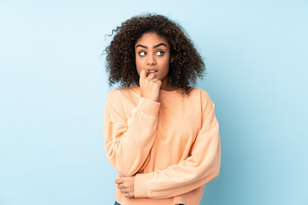 Jonge vrouw die op blauwe zenuwachtig en doen schrikken muur wordt geïsoleerd