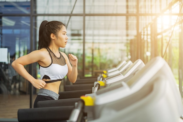 Jonge vrouw die op de loopband loopt in de sportschool