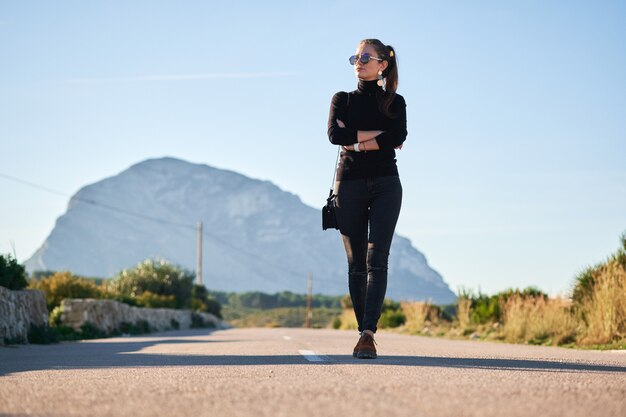 Jonge vrouw die op de weg tegen mooi uitzicht gaat