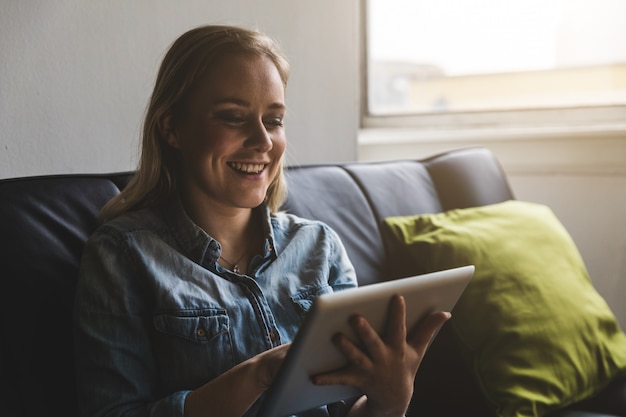 Jonge vrouw die op een digitale tablet thuis typen