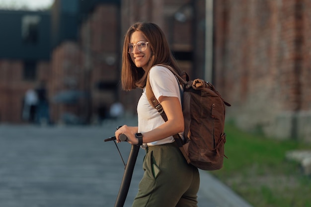 Jonge vrouw die op een elektrische scooter rijdt in de stadsstraat