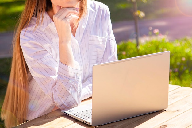 Jonge vrouw die op een laptop werkt op straat