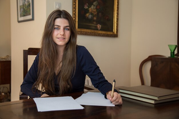 Jonge vrouw die op een leeg blad met een pen schrijft.