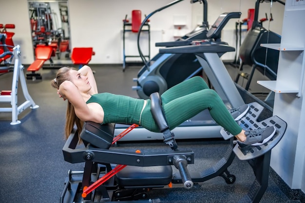 Jonge vrouw die op fitnessapparatuur traint in de sportschool Gezondheid sport en training concept